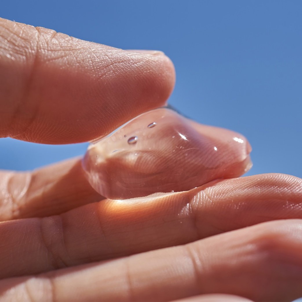 Hand holding a clear gel-like skincare product.